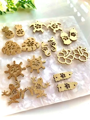 Dijes en varios diseños: coquí, amapola, tortuga, garita, mapa de PR, monsteras, caballito de mar, timón y piña / 18 piezas, 30mm, madera/MDF pintado en dorado brillante